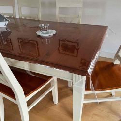 Holztisch mit Stühlen. Als Tischdecke dient tranparente Schutzfolie.