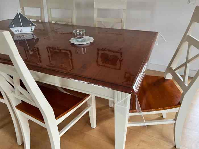 Holztisch mit Stühlen. Als Tischdecke dient tranparente Schutzfolie.