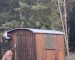 Bauwagen aus Holz auf einer Lichtung im Wald. Dach Baumhaus aus Holz im Wald. Dach ist abgedeckt mit grauer Abdeckplane.