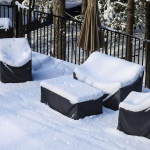 Schneebdedeckte Gartenmöblel welche mit Abdeckhaube abgedeckt sind.